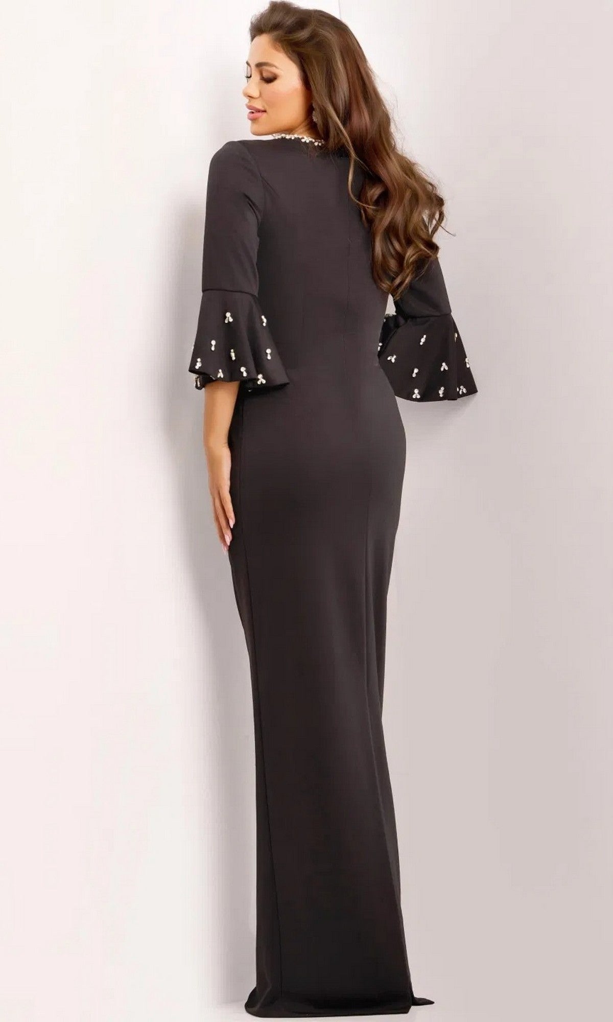 Woman in the Jovani 43826 long prom dress, a black jersey sheath with three-quarter crystal-beaded bell sleeves, shown standing with her back turned.